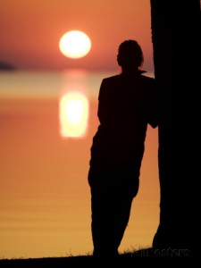 silhouette-of-a-woman-leaning-against-a-tree-trunk-on-the-beach